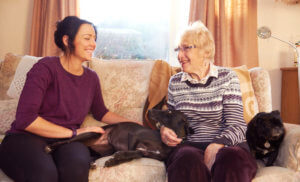 Live in care for younger people-old lady with dog and carer on the sofa